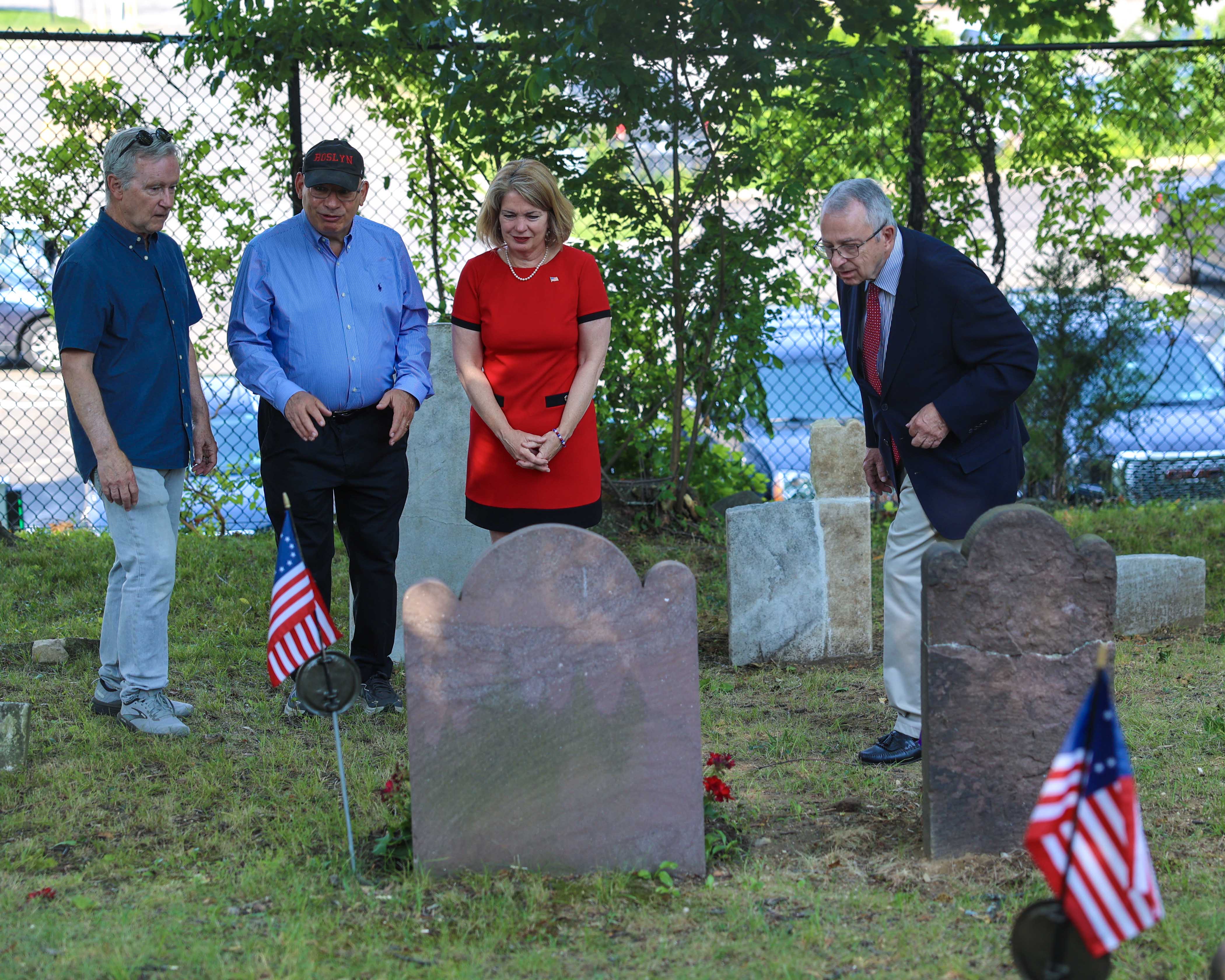 Supervisor DeSena and historians examine restored Revolutionary War gravestones at Monfort Cemetery.