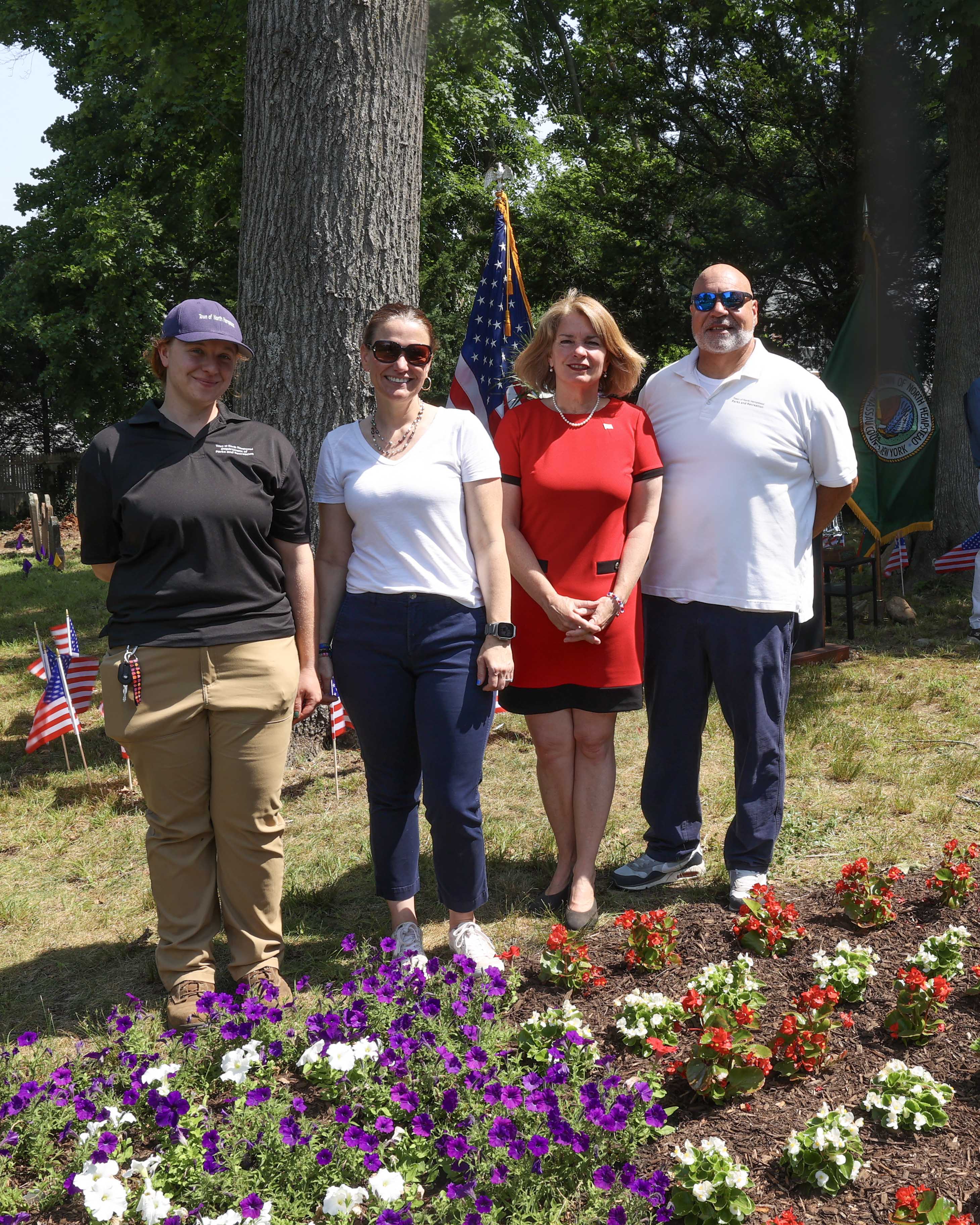 Supervisor Jennifer S. DeSena with Parks Department staff beside the red, white, and blue memorial gardens at Monfort Cemetery.