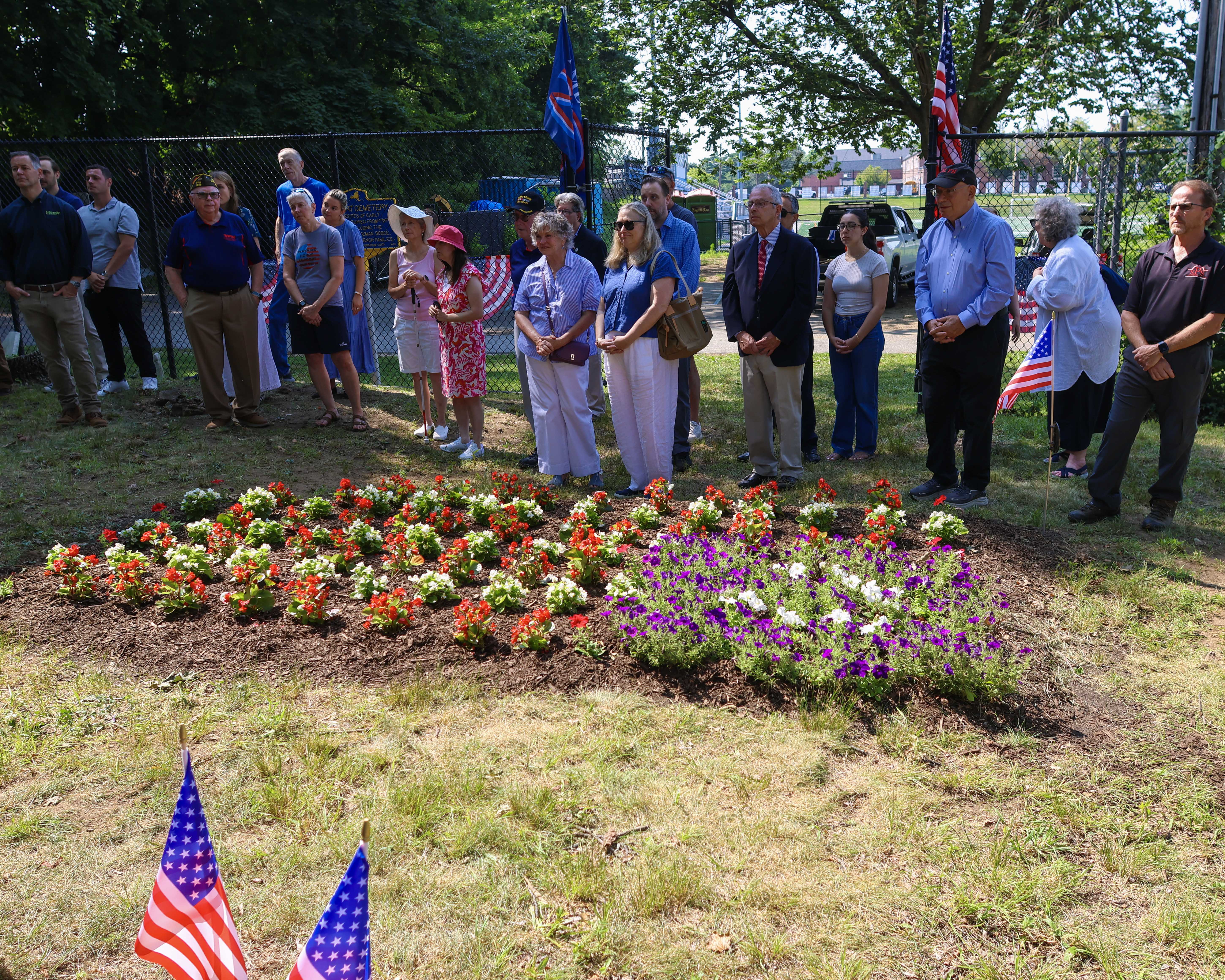 Attendees gather around the newly planted patriotic memorial garden during the Monfort Cemetery ceremony.