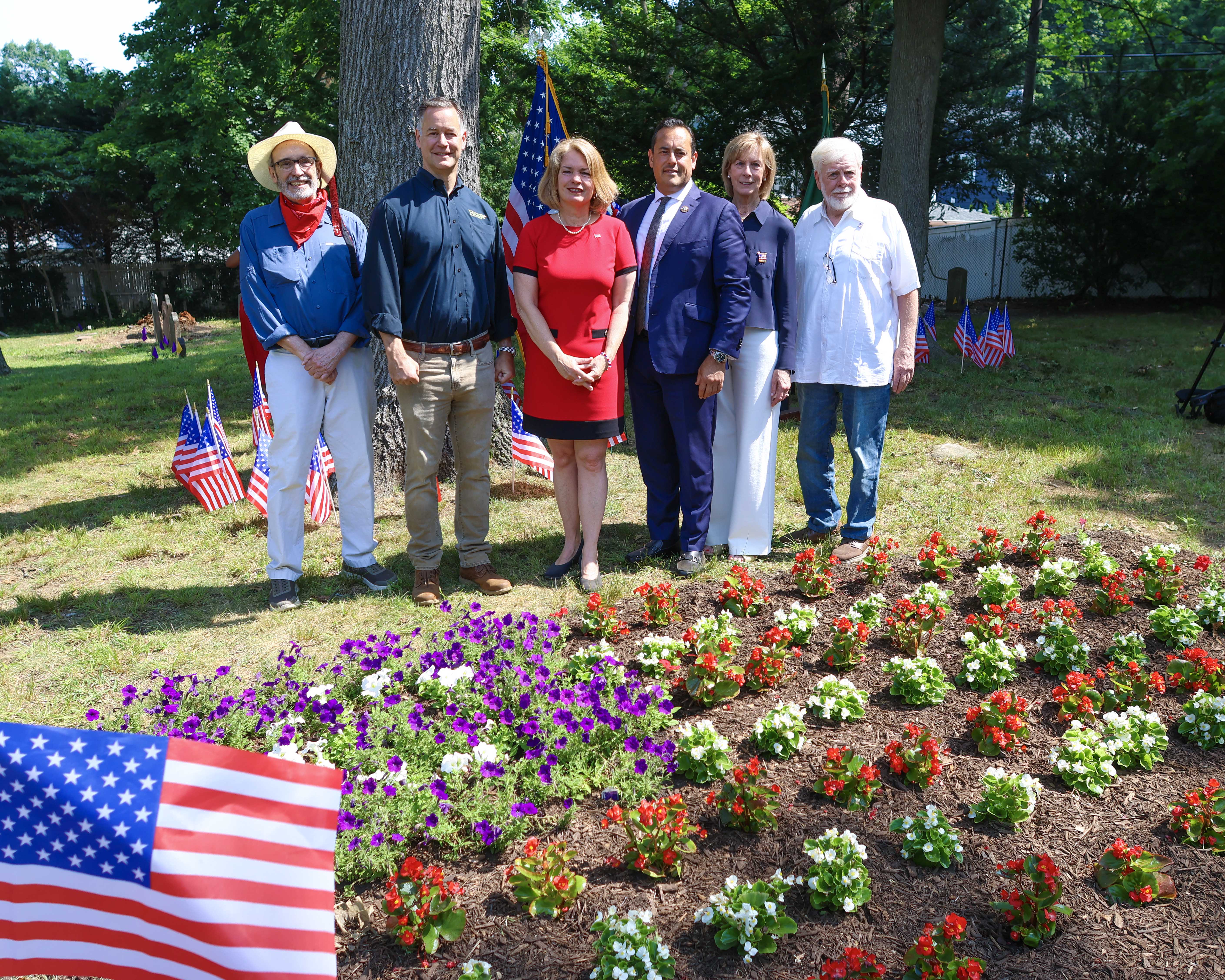 Supervisor DeSena with Town officials and Hicks Nurseries representatives in front of the newly planted red, white, and blue memorial gardens.