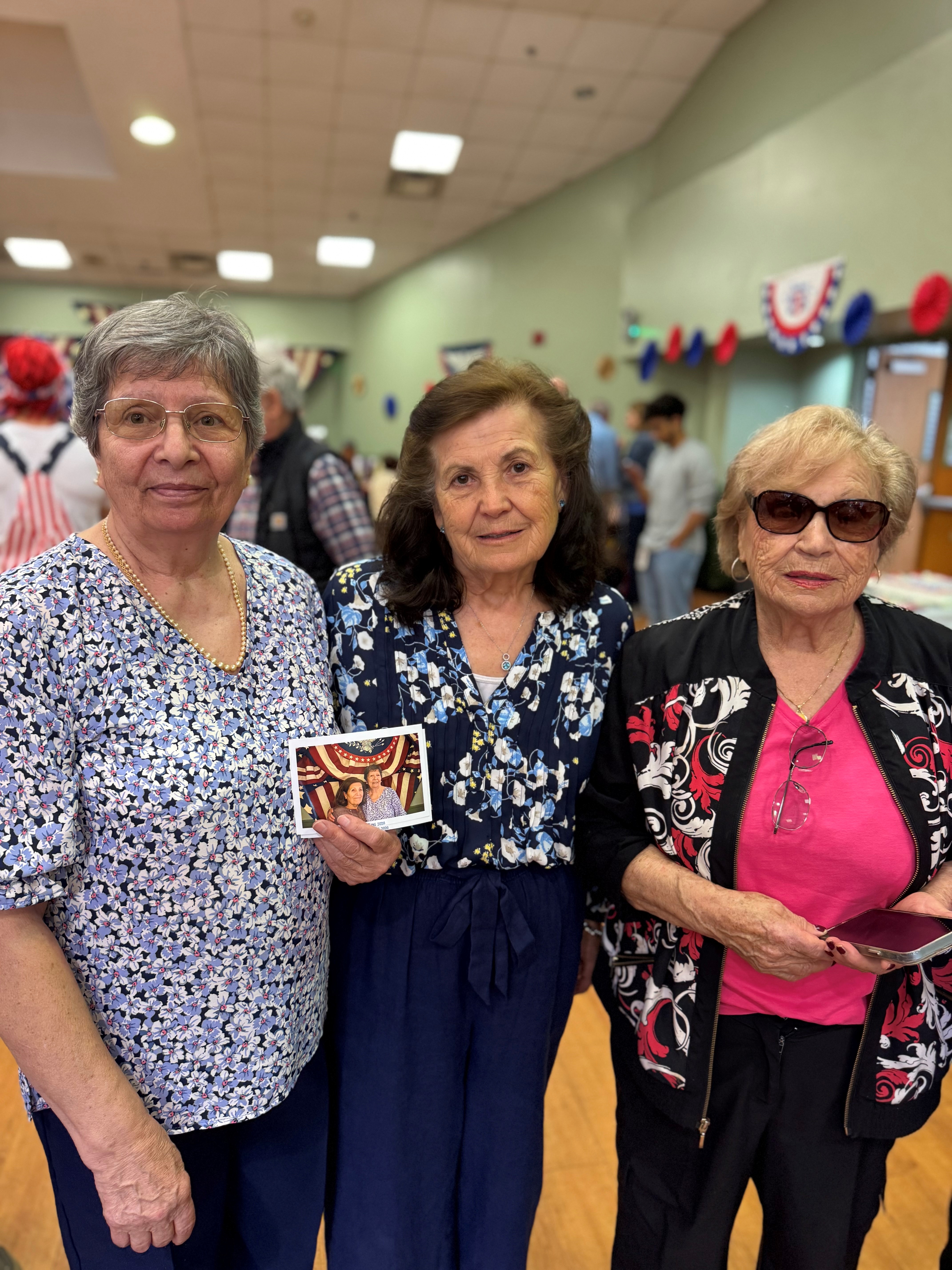 Three seniors pose together at the event; one holds a Polaroid photo taken earlier in the day.