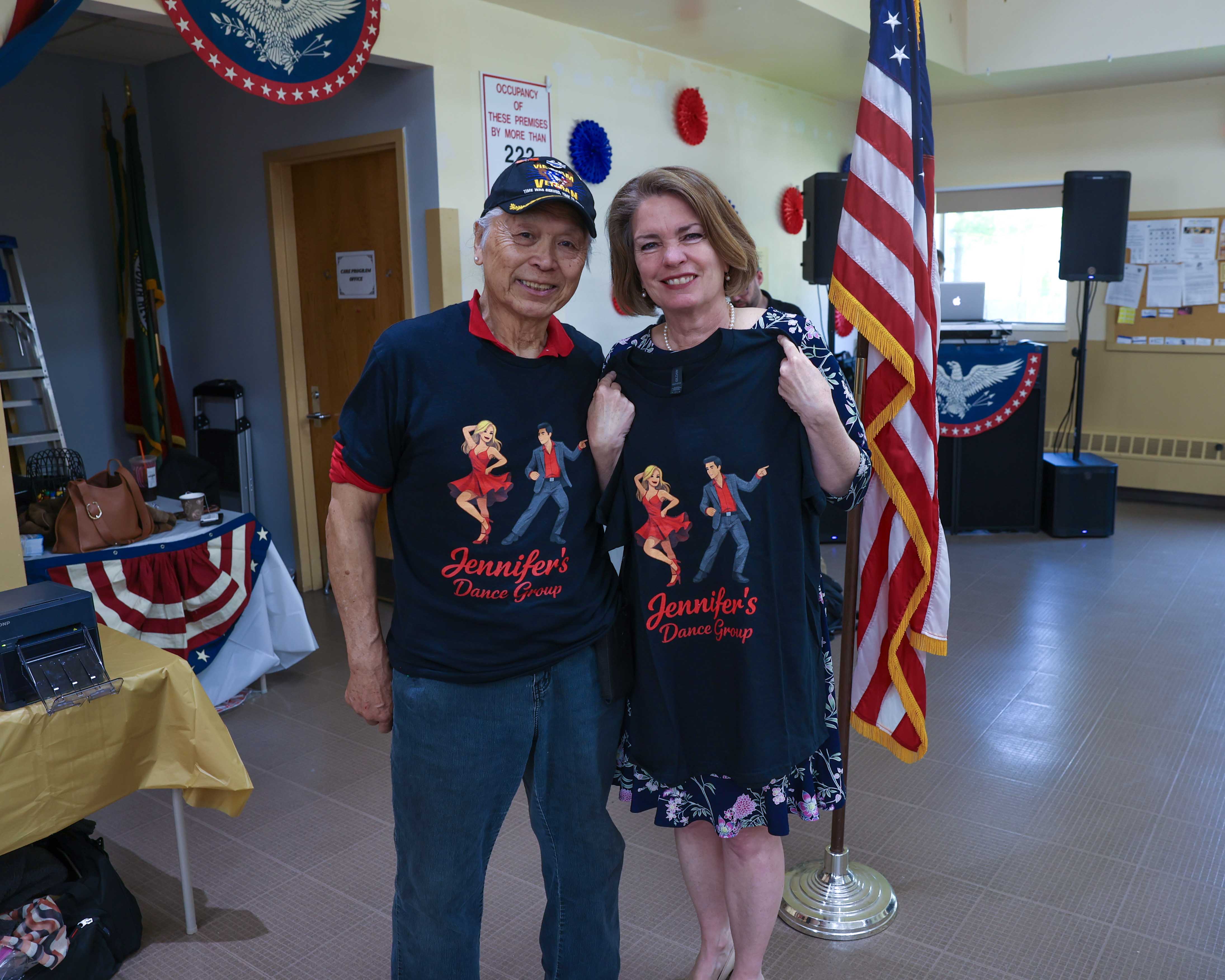 Supervisor Jennifer S. DeSena poses with a senior wearing a Jennifer's Dance Group t-shirt next to the American flag.