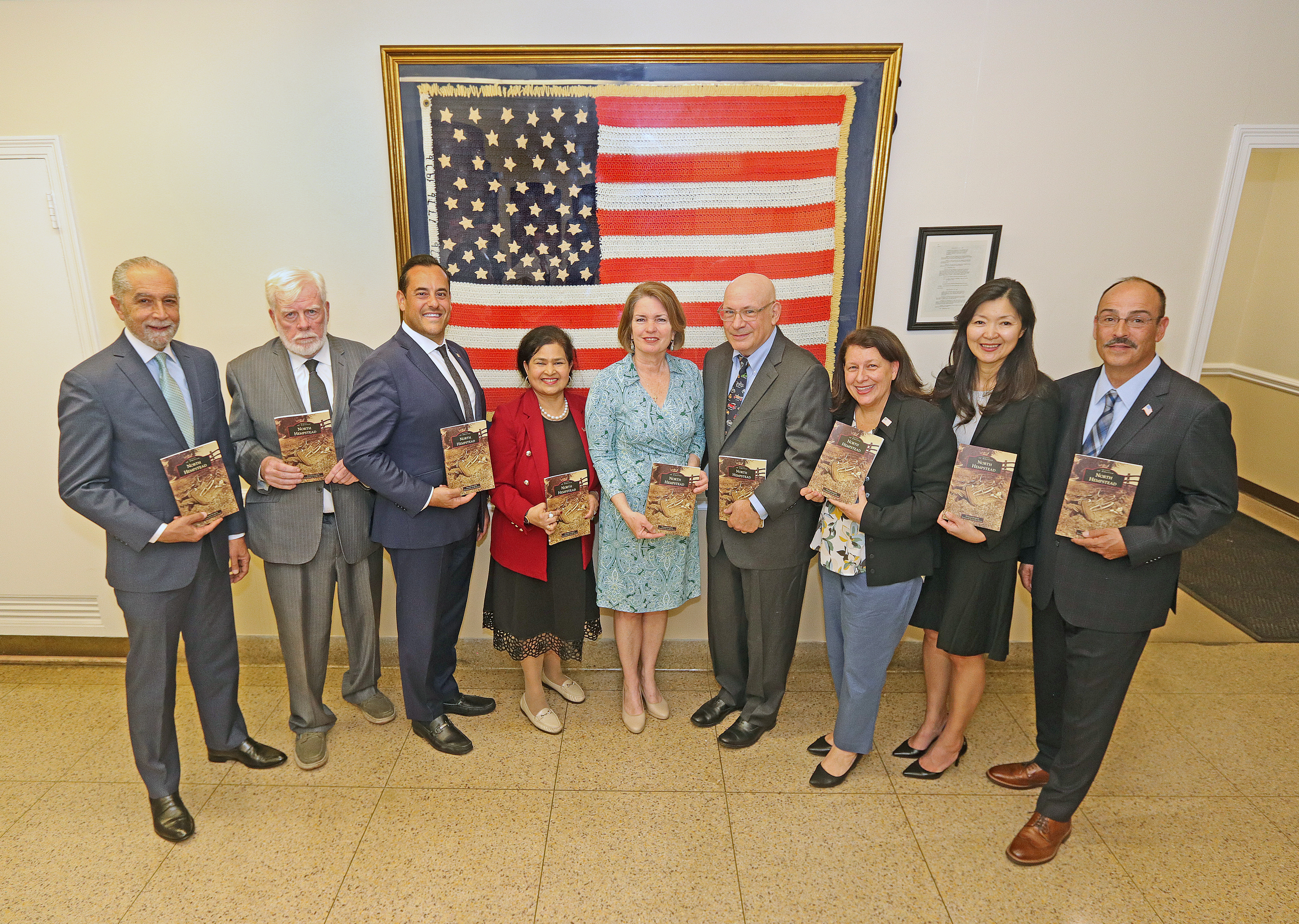 Supervisor Jennifer S. DeSena and the Town Board gathered in front of the crocheted American flag at the April 15, 2026 unveiling ceremony.